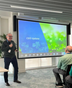 man giving a speech in front of projector screen