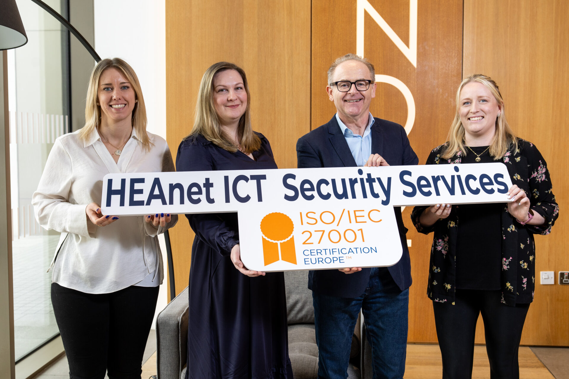 three women and a man holding a promotional sign