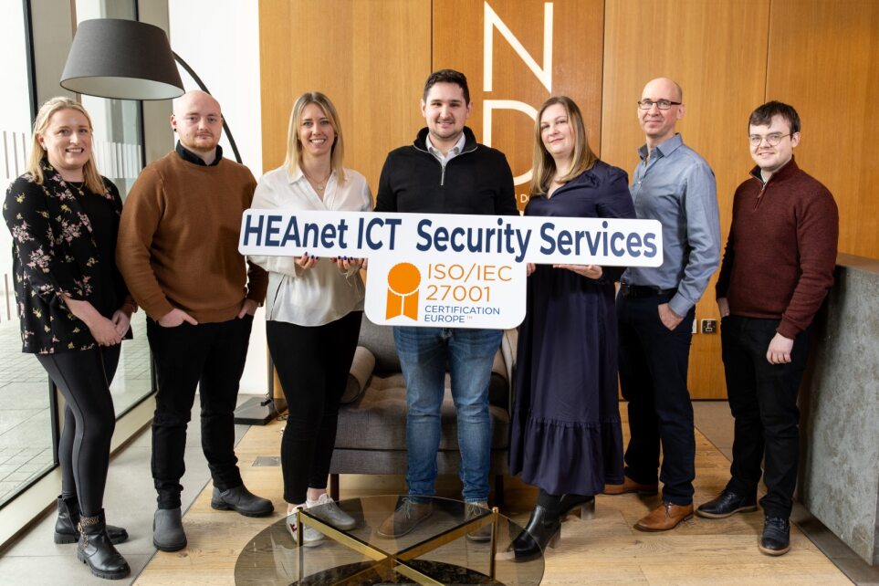 Group of men and women holding a promotional sign